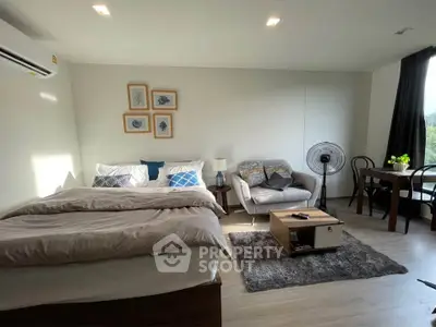 Modern studio apartment with cozy bed, stylish seating area, and dining table, perfect for urban living.