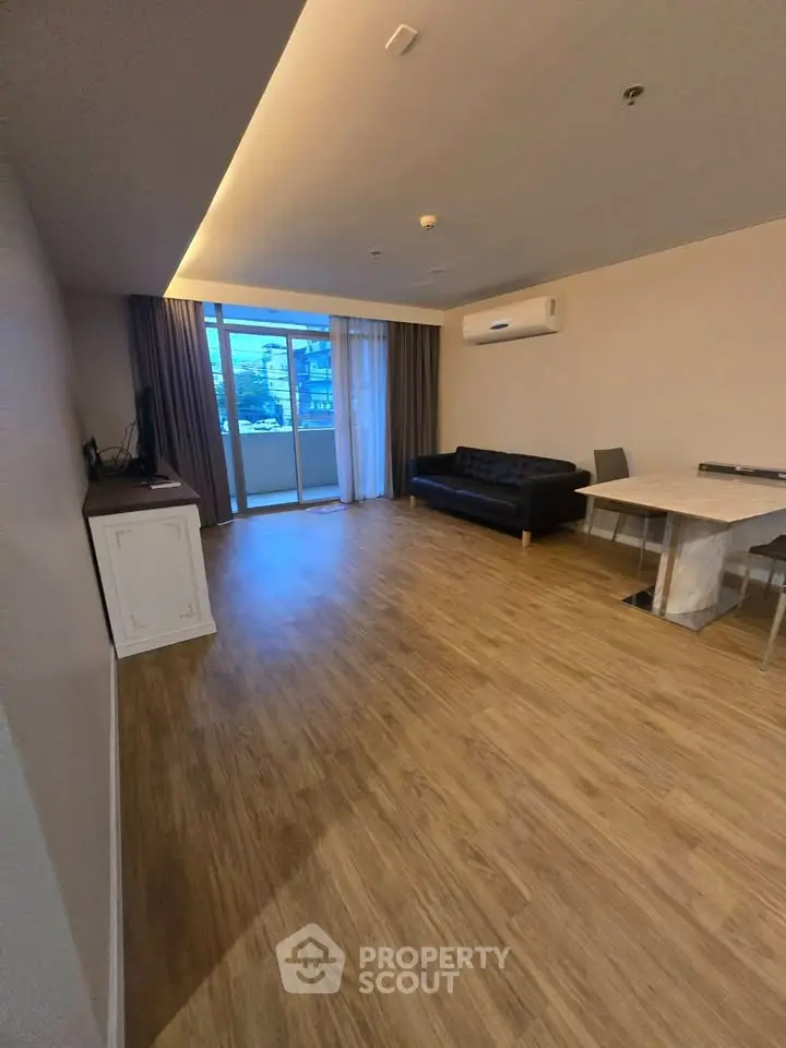 Spacious living room with wooden flooring and modern furniture in a stylish apartment.