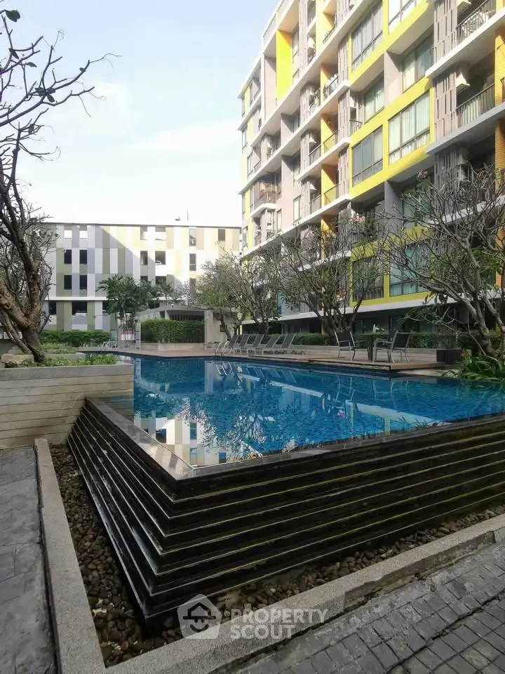 Modern apartment complex with stylish pool and landscaped surroundings.