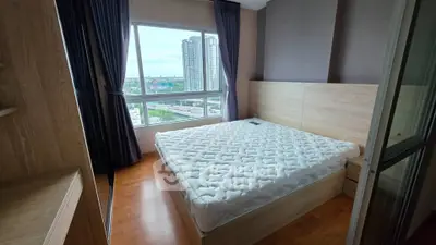 Spacious bedroom with large window offering stunning city views, featuring a comfortable bed and elegant wooden flooring.