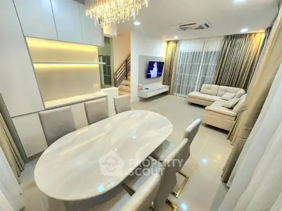 Luxurious open-plan living and dining area with elegant chandelier and modern furnishings.