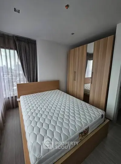 Modern bedroom with large window and wooden wardrobe in a high-rise apartment.