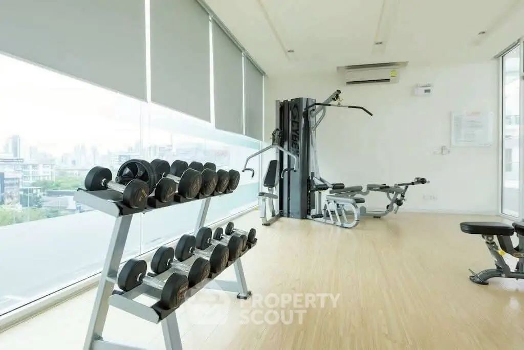 Modern gym with city view and fitness equipment in luxury apartment building.