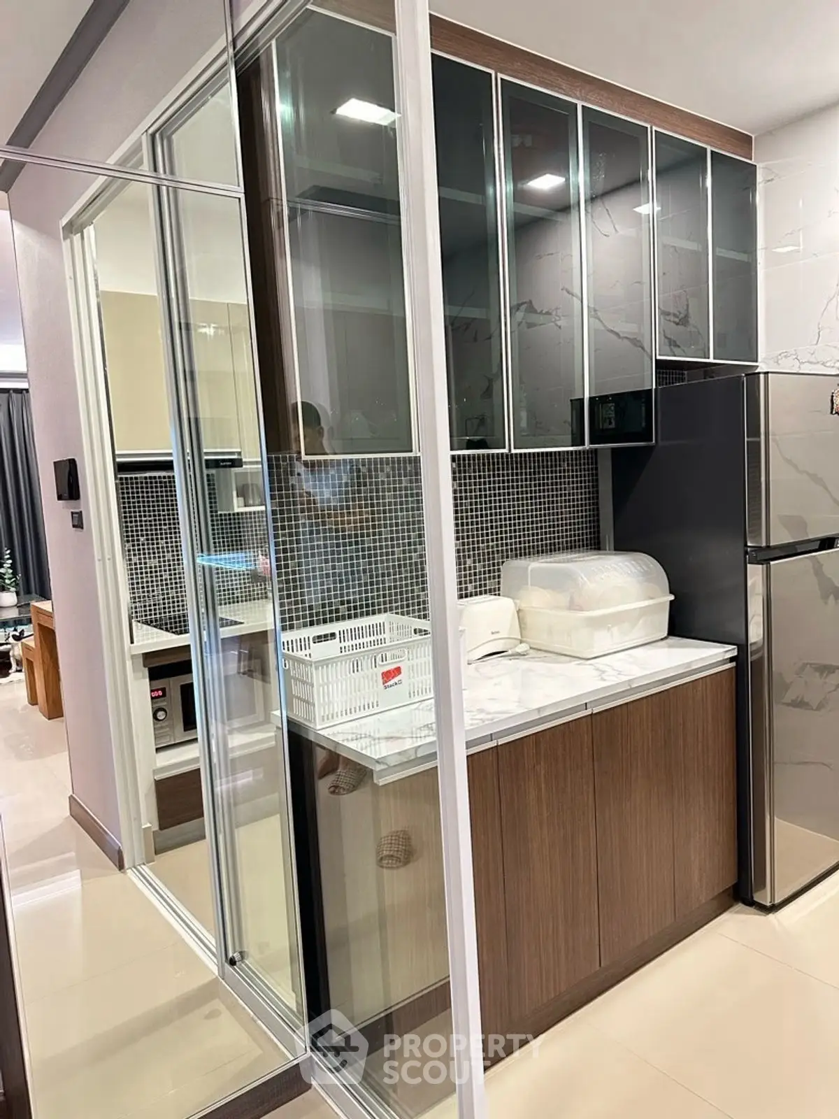 Modern kitchen with sleek cabinets and glass doors, featuring a compact design and stylish finishes.