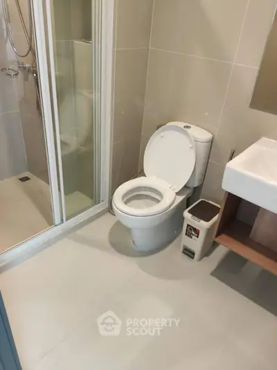 Modern bathroom with shower, toilet, and sink in sleek design.