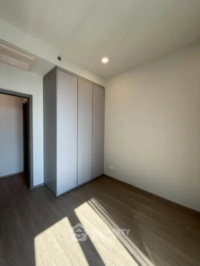 Spacious empty room with built-in wardrobe and natural light, perfect for customization.