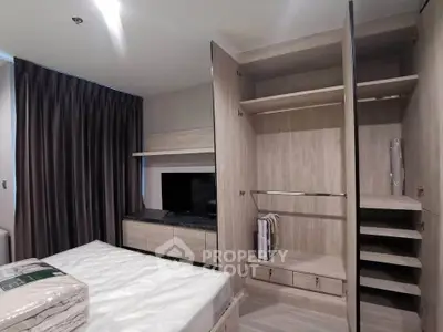 Modern bedroom with open wardrobe and sleek TV unit, showcasing stylish interior design.