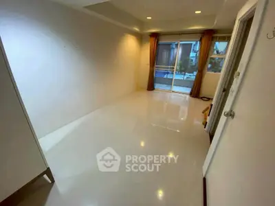 Spacious unfurnished room with glossy floors and large window leading to balcony.