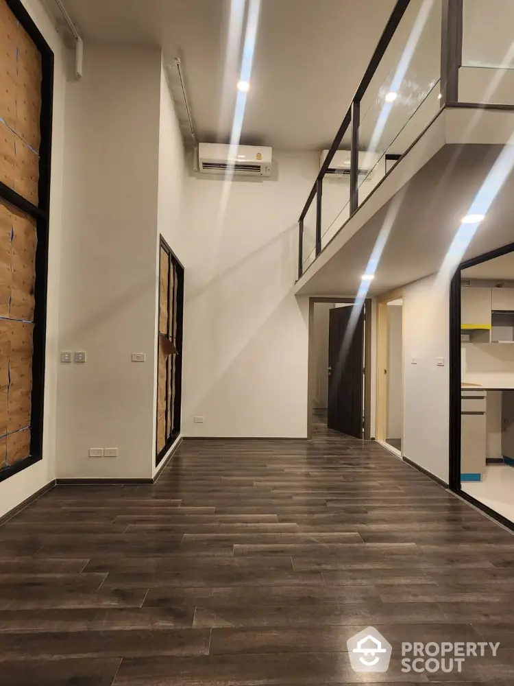 Modern loft apartment with high ceilings and mezzanine level, featuring sleek wooden flooring and contemporary design.