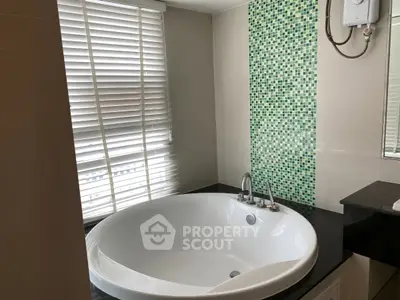Luxurious bathroom with a stylish bathtub and modern mosaic tile accent wall.
