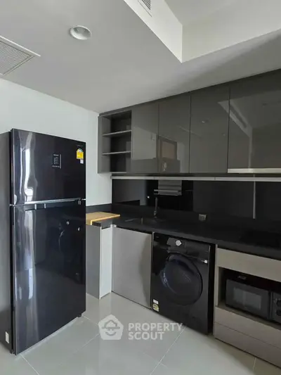 Modern kitchen with sleek black appliances and glossy cabinets in a contemporary apartment.