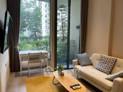 Modern living room with large windows and garden view, featuring cozy sofa and stylish decor.