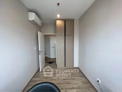 Minimalist bedroom with wooden flooring and built-in wardrobe in modern apartment.