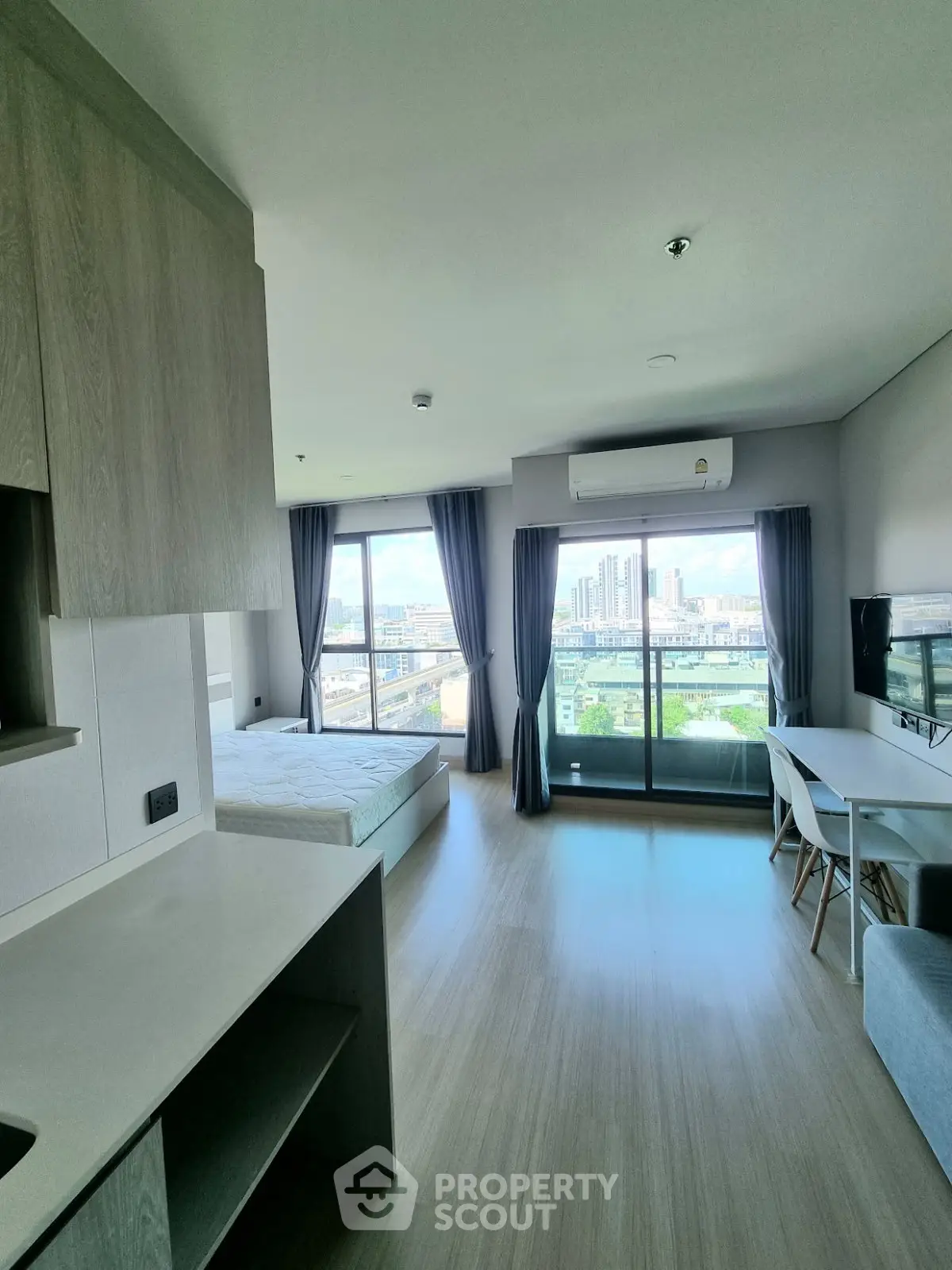 Modern studio apartment with open layout and stunning city view from balcony.
