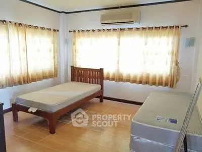 Bright bedroom with twin beds and air conditioning, ideal for comfort and relaxation.