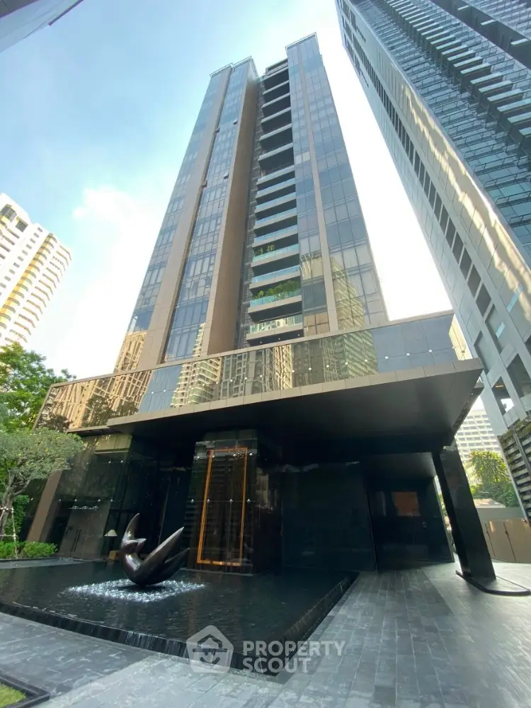 Stunning modern high-rise building with sleek glass facade and elegant entrance fountain.