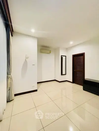 Spacious empty room with tiled floor and air conditioning, ideal for customization.