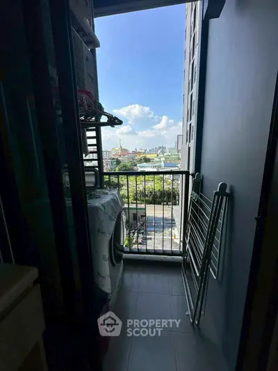 Compact balcony with washing machine and city view, ideal for urban living.