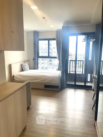 Modern studio apartment with balcony and city view, featuring sleek wooden flooring and contemporary furnishings.