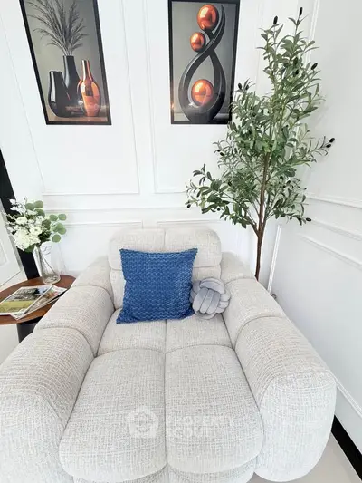 Elegant living room with plush white sofa, blue cushion, and modern art decor.