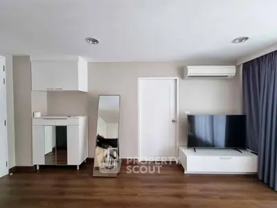 Modern living room with sleek TV setup and stylish mirror on wooden flooring.