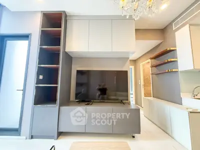 Modern living room with sleek cabinetry and large TV, featuring elegant lighting and contemporary design.