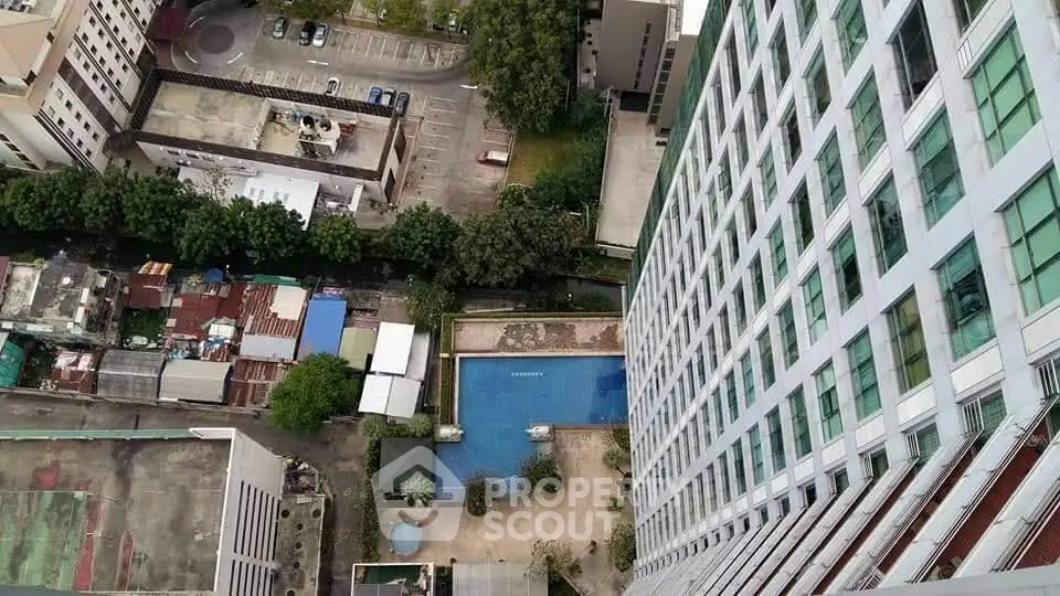 Stunning aerial view of modern high-rise building with pool and parking area, perfect for urban living.