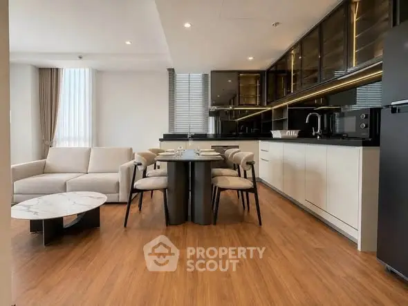 Modern open-layout kitchen and living room with sleek design and wooden flooring.