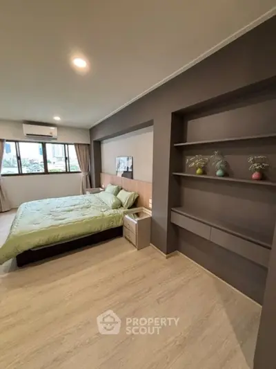 Spacious modern bedroom with built-in shelves and large windows.