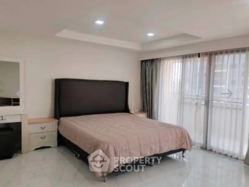 Spacious bedroom with modern decor and large windows for natural light.