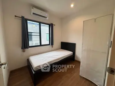 Cozy minimalist bedroom with single bed and air conditioning, perfect for a peaceful retreat.