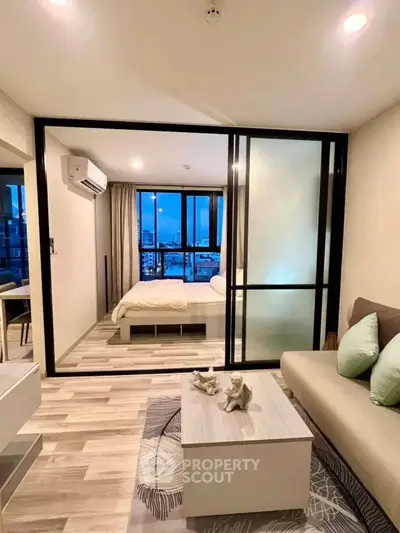 Modern apartment interior with cozy living room and stylish bedroom separated by glass partition.