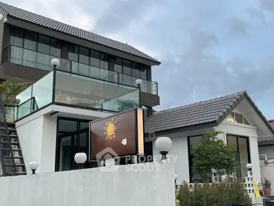 Modern two-story house with glass balcony and stylish exterior design.