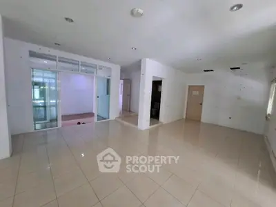 Spacious empty living room with tiled flooring and glass partition, ready for customization.