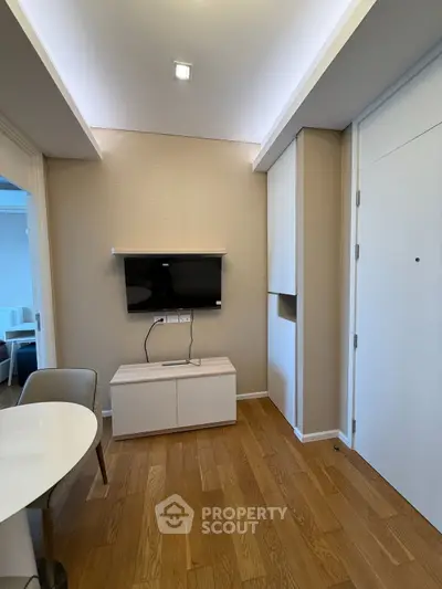 Modern living room with hardwood floors and wall-mounted TV in a stylish apartment.