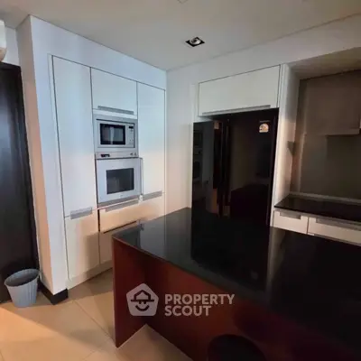 Modern kitchen with sleek appliances and black countertop in a stylish home.