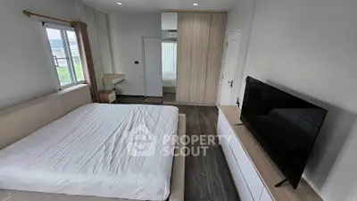 Spacious bedroom with modern furnishings and large window view.