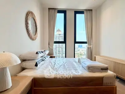 Modern bedroom with large windows offering city views, featuring stylish decor and natural light.