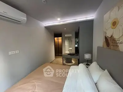 Cozy bedroom with modern decor and air conditioning, featuring a stylish painting and soft lighting.