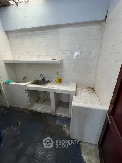 Simple kitchen with tiled countertops and sink in a modest home setting.