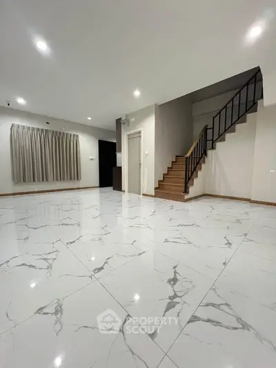 Spacious modern living room with elegant marble flooring and staircase