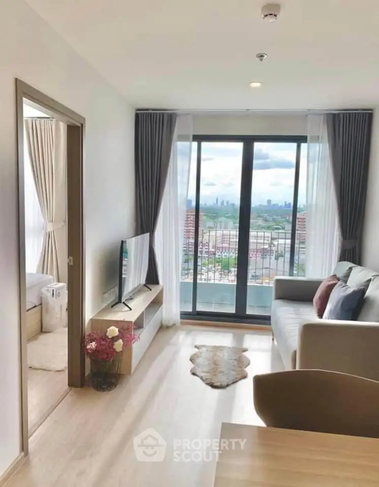 Modern living room with city view, stylish decor, and natural light in a high-rise apartment.
