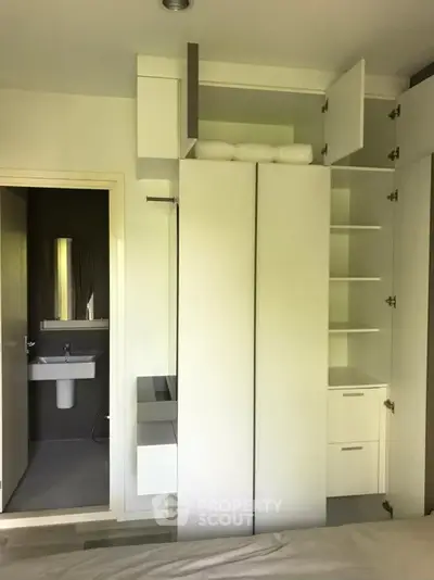 Modern bedroom with built-in storage and en-suite bathroom, featuring sleek white cabinetry and contemporary design.