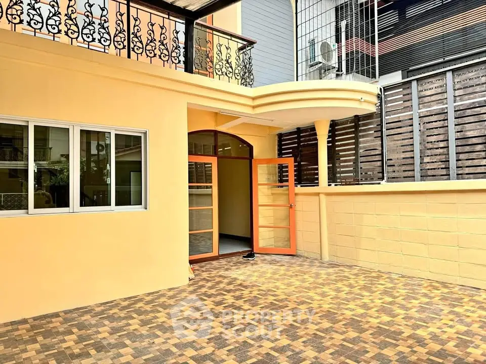 Charming townhouse with spacious patio and elegant ironwork balcony.