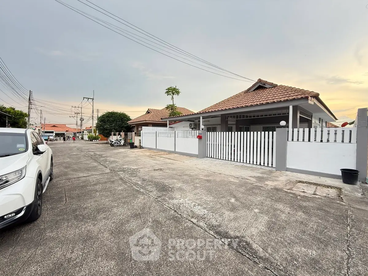 Charming suburban house with tiled roof and white picket fence in a quiet neighborhood.