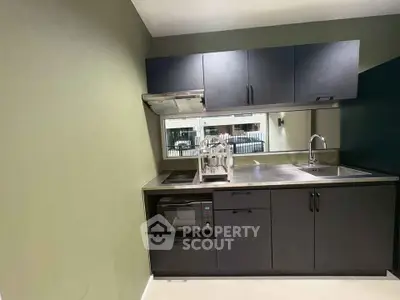 Modern compact kitchen with sleek black cabinets and stainless steel appliances.