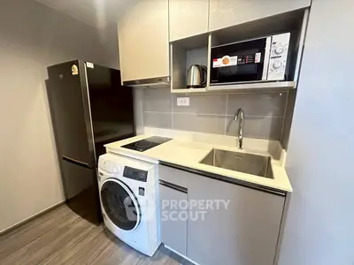 Modern compact kitchen with appliances including fridge, washing machine, and microwave in sleek design.