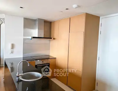 Modern kitchen with sleek cabinetry and built-in oven, featuring a stylish black countertop.