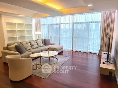 Spacious modern living room with large windows and city view, featuring elegant furniture and warm lighting.