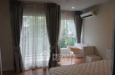 Bright bedroom with large windows, elegant curtains, and a cozy workspace.